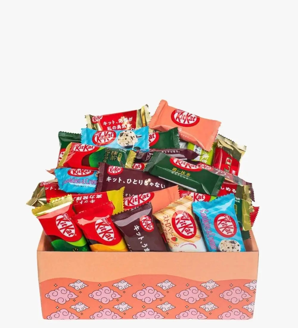 Et livligt udvalg af kitkat-chokoladebarer i forskellige smage og farverige indpakninger, gemt inde i en lyserød gaveæske med mønster.