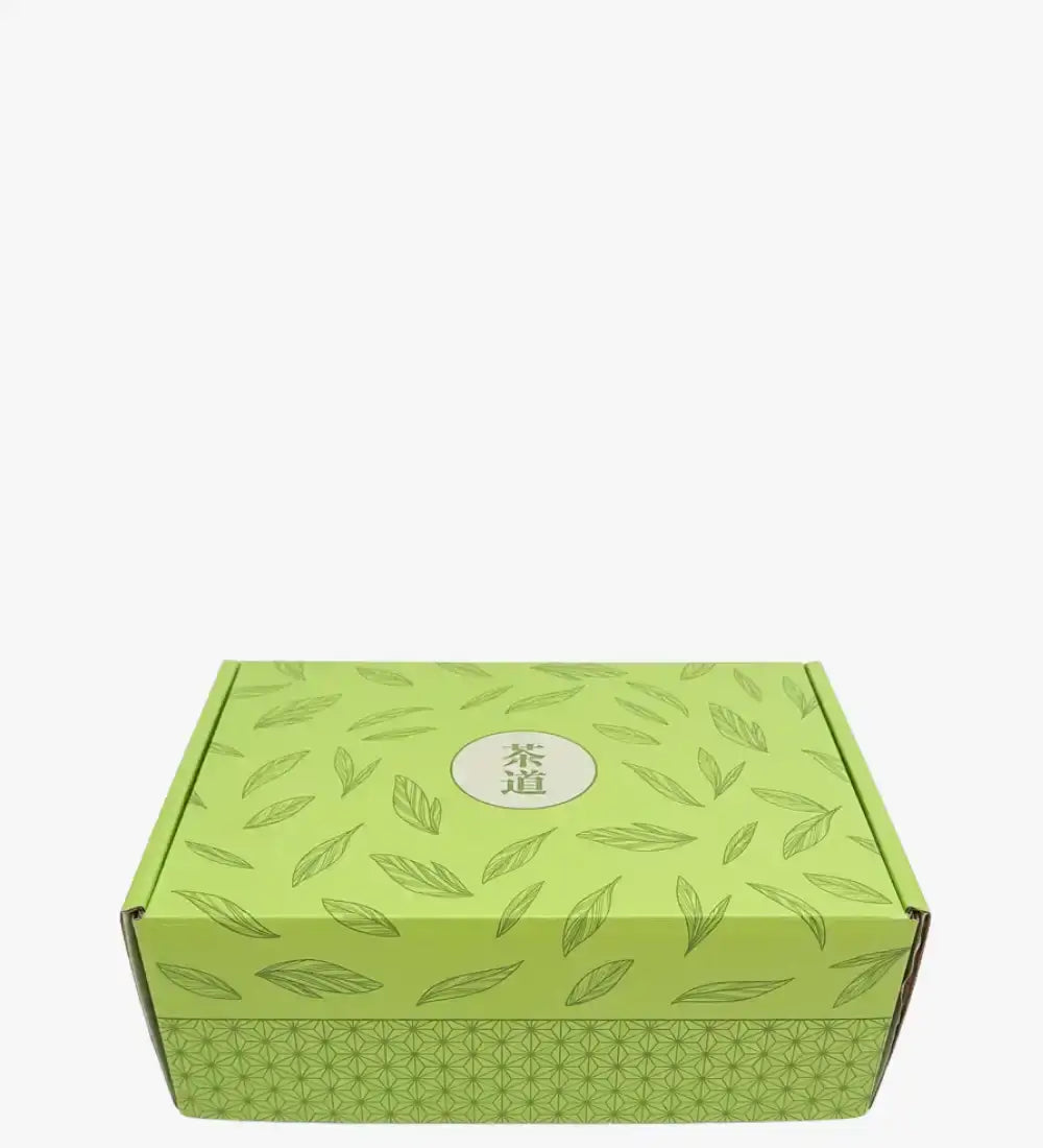 Boîte de thé à motif de feuilles vertes avec un logo circulaire.